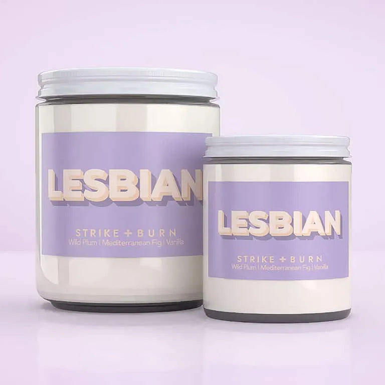 Two white jar candles with lavender labels reading 'LESBIAN STRIKE + BURN' on a soft lavender background.